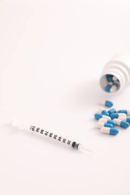 Beyaz arkaplanda izole edilmiş şırınga ve hap