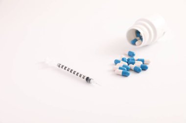 Beyaz arkaplanda izole edilmiş şırınga ve hap