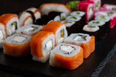 Farklı ekmekler, Philadelphia 'da somon ve peynirle kaplanmış siyah bir arka planda Japon mutfağı.