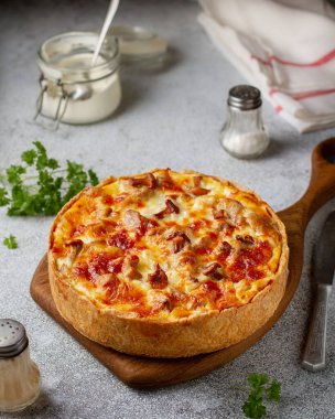 Kısa hamurlu hamur tatlısı, mantarlı mantar ve peynirli, ahşap bir tahtanın üzerinde kahverengi kabuklu, yakın plan, otların ve baharatların yanında.