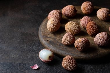 Liçi meyvesi soyulmuş ve ahşap bir tahtanın üzerinde hamurla soyulmuş. Koyu arkaplan, boş alan.