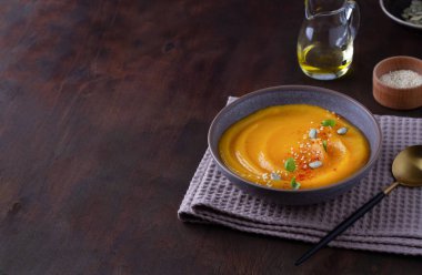 Tahta bir masada seramik tabakta kabak püresi çorbası, kopyalama alanı.