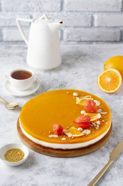 Beyaz ahşap bir masada, portakallarla süslenmiş, balkabağı kremalı turta.