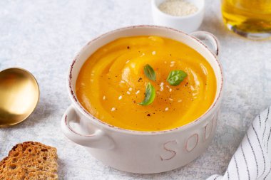 Gri bir masadaki saksıda otlu balkabağı çorbası, yakın plan.