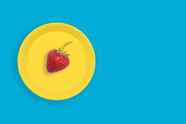 Taze çilek sarı bir plaka üzerinde fotokopi alanı olan turkuaz bir arka planda..