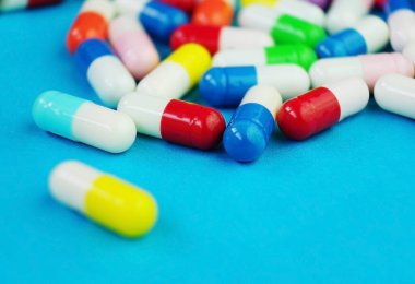 Mavi arka planda haplar ve kapsüllerden oluşan detaylı bir makro.