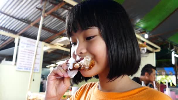 Asian girl eating fried chicken. — Stock Video