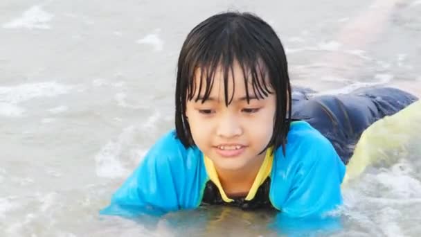 Asian kid splashing in the surf on beach. — Stock Video