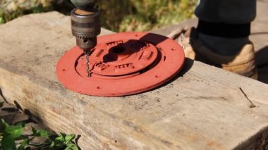 Adam metalde bir delik kazıyor. Araba debriyajı diski. Bir matkapla çalış.