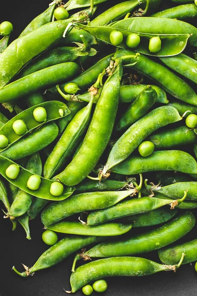 Siyah arkaplanda bezelyeler. Bir tabakta bezelye. Yaz meyveleri. Yeşil ve siyah