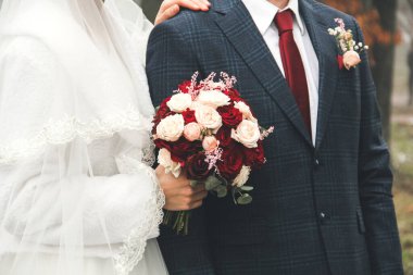 Gelin ve damat birlikte yaklaşın. Düğün buketi olan gelin. Gelinlik ve kırmızı kravat.