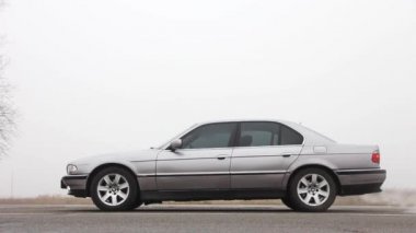 Chernigov, Ukrayna - 6 Ocak 2021: farları açık araba. Eski araba BMW 7 Serisi (E38) sisli bir zemine karşı yolda. Kasvetli hava