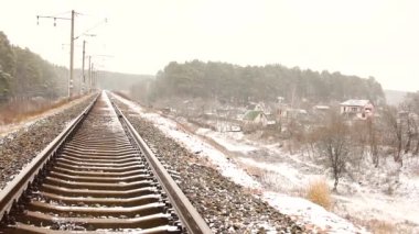 Tren yolu, köy ve ormanın arka planına karşı. Kış.