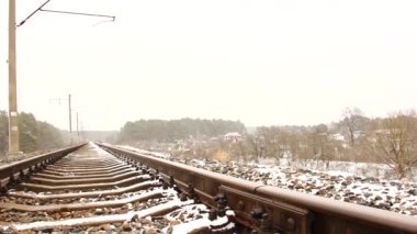 Tren yolu, köy ve ormanın arka planına karşı. Kış.