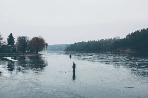 A fisherman on a frozen river is fishing.