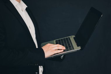 Elinde dizüstü bilgisayarla takım elbiseli bir iş adamı. Dizüstü bilgisayarı olan adam