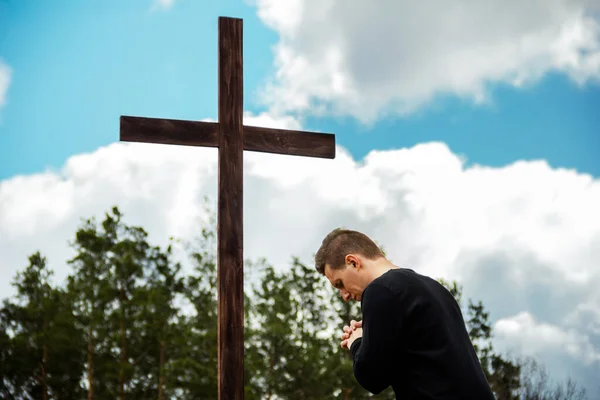 A man prays near the cross. Man believes in God. Hope in God