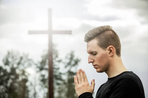 A man prays against the background of the cross. Man believes in God. Hope in God