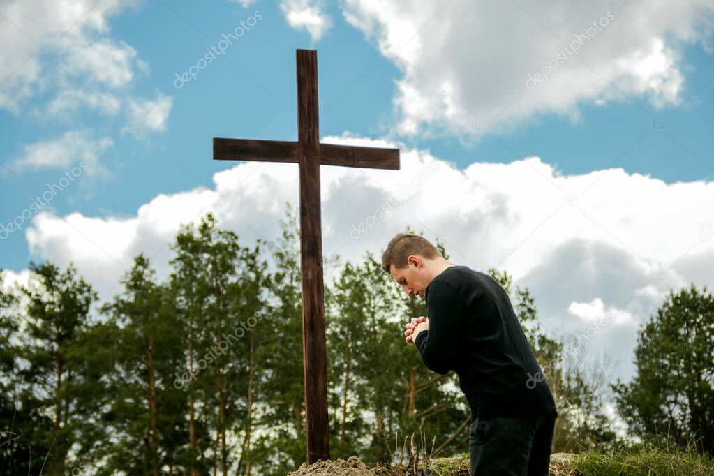 A man prays near the cross. Man believes in God. Hope in God