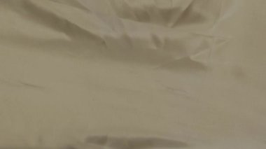 Saten bej kumaş arka plan. Dalgalı ipek kumaş. Kumaşın yavaş hareketi