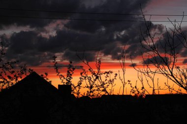 Güzel akşam gün batımı. Ağaçların dalları ve gölgelerde evler. Pencereden görüntüle