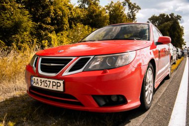 Chernigov, Ukrayna - 24 Temmuz 2021: Saab araçları yolda. Ağaçların arkasında kırmızı Saab 9-3 arabası