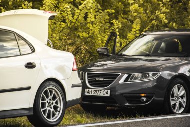 Chernigov, Ukrayna - 24 Temmuz 2021: Saab araçları yolda. Gri Saab 9-5 2010 ve beyaz Saab 9-3 ağaçların arka planında