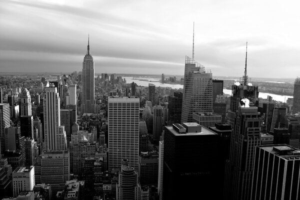 Horizontal aerial view of the Manhattan section of New York City including all of the buildings and skyline in black and white.