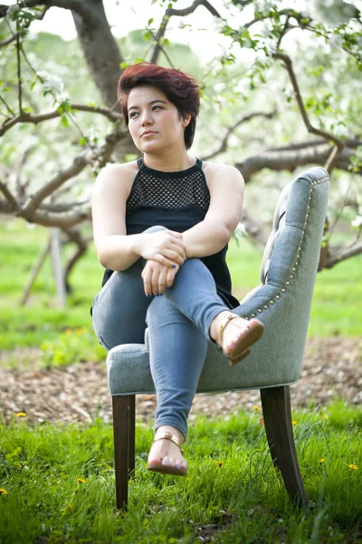 Brunette femme sur une chaise à l'extérieur — Photo