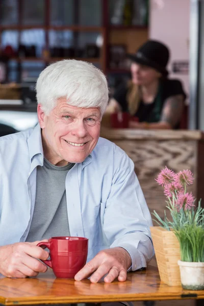 Volwassen man zit in koffiehuis — Stockfoto