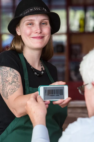 Barista segurando telefone com código de cupom — Fotografia de Stock