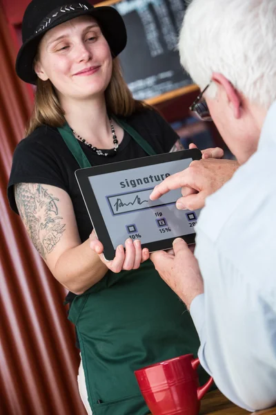 Zralý muž znamení Tablet zaplatit účet v Cafe — Stock fotografie