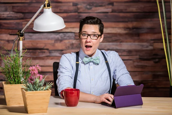 Aufgeregte Frau am Schreibtisch mit Tablet — Stockfoto