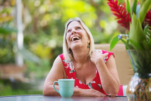 Smějící se ženu sedící u stolu — Stock fotografie