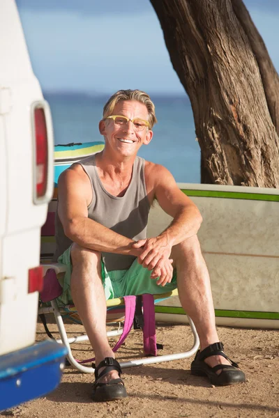 Sonriente adulto sentado con tabla de surf —  Fotos de Stock