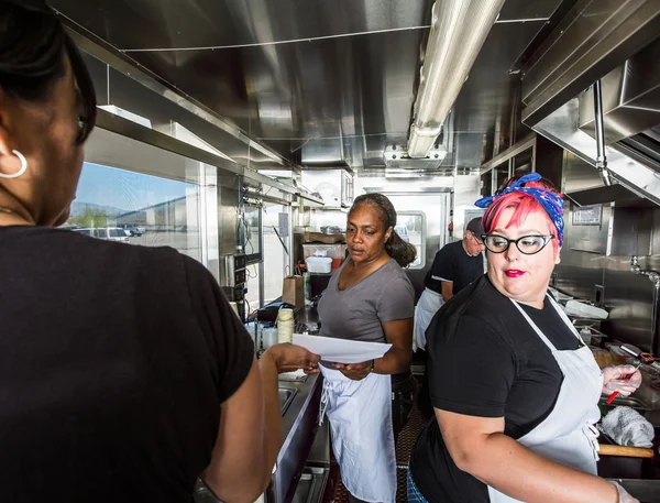 Chef trabalha ao lado da tripulação em caminhão de comida — Fotografia de Stock
