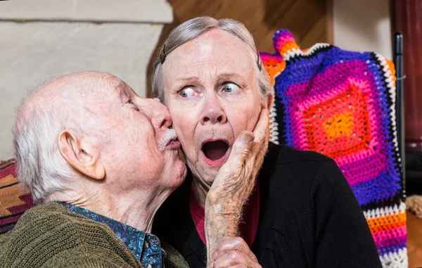 Older gentleman kissing shocked woman — Stock Photo, Image