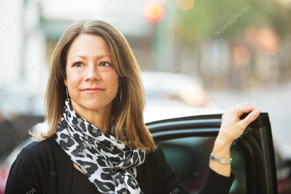 Confident businesswoman standing near car