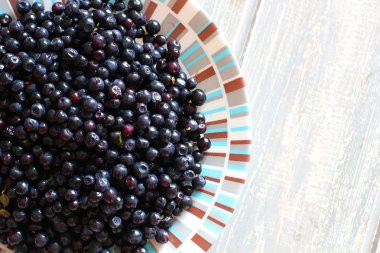 Bilberries ahşap gri masa üzerinde beyaz plaka.
