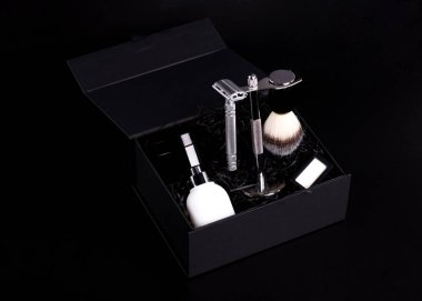 Jilet ve fırça tezgahta, parfüm, balsam ve siyah arka planda siyah kutuda bıçaklar..