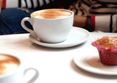 Kafedeki masada iki fincan kahve ve kek var.