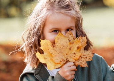Sonbahar parkında yaprakları atan mutlu kız.