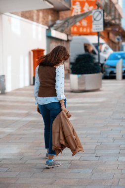 Deri ceketli ve kot pantolonlu Asyalı bir kadın Avrupa 'da dolaşıyor.