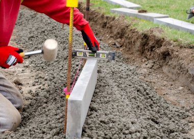 Yol çalışması sırasında yarı yarıya betonun kenarındaki kaldırım ve güvenlik eldiveni takan toprak işçisinin yeni yaya yolu inşaatı.
