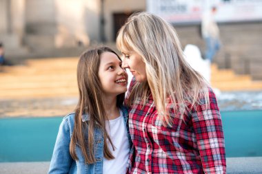 Anne ve kız güneşli bir günde şehirde birbirleriyle konuşuyorlar.