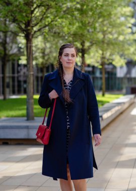 Paltolu bir kadın bahar günü sokakta yürüyor.