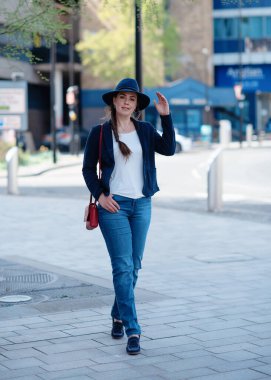 Paltolu bir kadın bahar günü sokakta yürüyor.