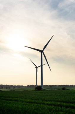 İngiltere 'de bulutlu mavi gökyüzüne karşı yeşil alanda yel değirmenleri üreten bir elektrik.