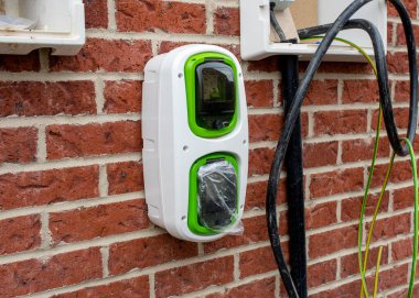 Elektrikçi tarafından bağlanmayı bekleyen yeşil enerji programının bir parçası olarak evin dışına yeni konut geliştirme üzerine kurulmuş elektrikli araç yerli şarj noktası