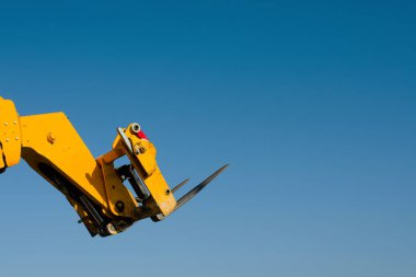 Teleskopik Forklift 'in çatalları mavi gökyüzü arkaplanında yükseltildi